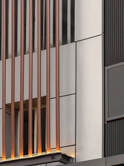 A close-up view of the material details. The softness of the smooth ACP panels is juxtaposed with the linear rawness of the metal louvers, creating an elegant and ordered composition.
