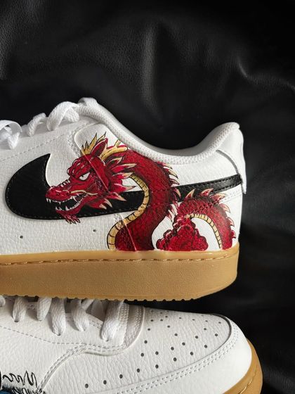 A close-up of a custom Nike Court Vision sneaker with a fierce red dragon design.