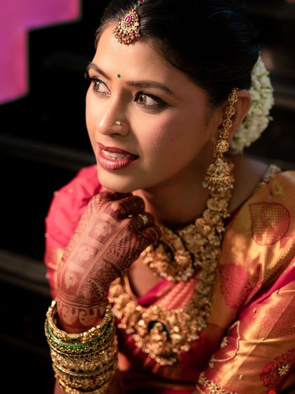 A close-up portrait highlighting the intricate eye makeup and the beautiful temple jewelry. The look is both traditional and incredibly glamorous.