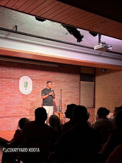 A full house for Nishant Suri's stand-up show. The audience is silhouetted, their attention fully on the comedian, capturing the immersive experience of a live comedy night at Koota.