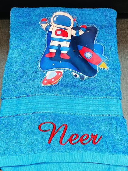 This astronaut-themed towel is perfect for a little space explorer. The bright blue towel is embroidered with their name in red.