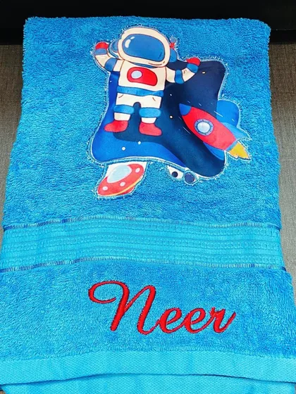An astronaut themed towel for your little space explorer. This bright blue towel is personalised with the name 'Neer' and a cool astronaut patch.