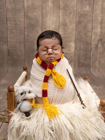 Our little Harry Potter is dreaming of casting spells. This version of the theme places the swaddled newborn in a miniature bed, ready for a magical slumber.