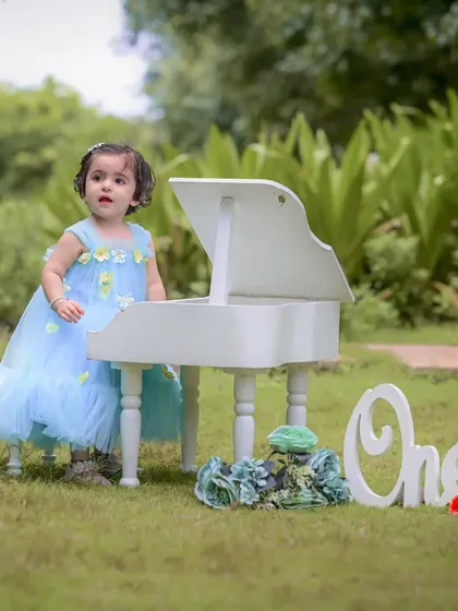 Celebrating a first birthday is a huge milestone. For this outdoor session, we used a mini white piano and a "One" sign to create a sweet, memorable scene for Naira's special day. Milestone photography is about celebrating these precious firsts.
