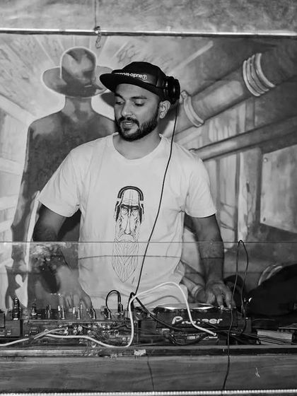 A classic black and white photo from behind the decks. It captures the timeless feel of a DJ at work, focused on the craft of mixing music and creating a vibe.