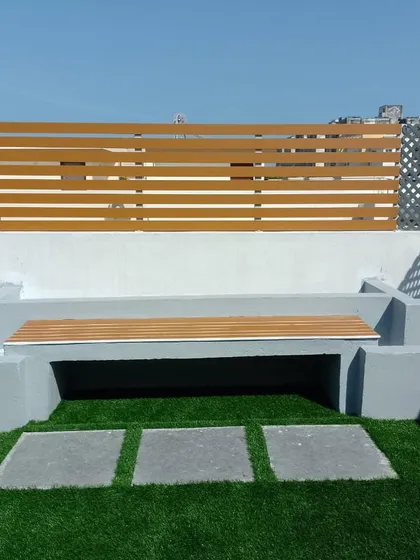 A simple built-in bench made of concrete and wood composite provides durable and stylish seating on this terrace. Paired with artificial turf and stone pavers, it creates a clean, modern look for this party space.