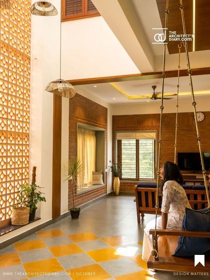 The living room of the Vivek Residence, where a traditional swing sits on a floor of Kota stone with yellow Jaisalmer inlays. The double-height jali wall filters light beautifully into the space.