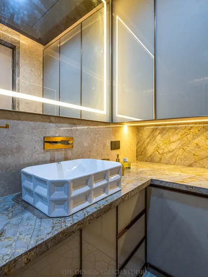 A close-up of the designer washbasin and the warm, ambient lighting from the backlit mirror and under-cabinet LEDs. These details create a luxurious and inviting atmosphere.