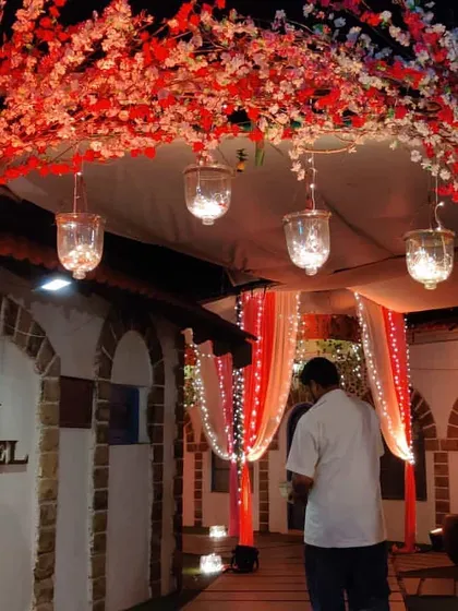 The entrance to a beachside wedding, framed by an arch of artificial cherry blossoms. The red and white flowers create a beautiful and romantic welcome for guests arriving at the Juhu hotel.