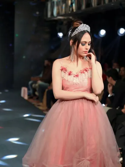 A candid moment on the runway. The soft lighting catches the layers of the pink tulle gown, showcasing the movement and texture of the fabric as the model walks.