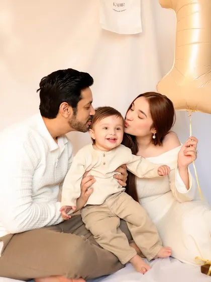 Parents kiss their smiling son's cheeks in a loving family portrait from his first birthday session. This image is a beautiful expression of family love and celebration.