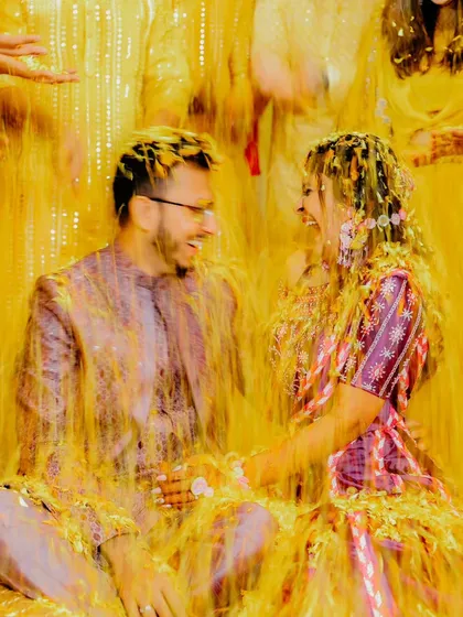 A candid moment of the couple laughing together, covered in turmeric and flowers. This is what a fun-filled haldi looks like.