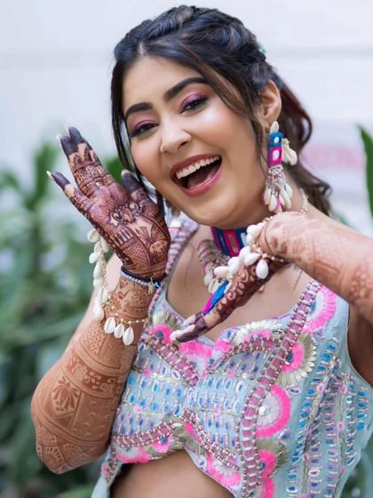 A happy bride showing off her beautiful mehandi. Her smile and the intricate design on her hands are a perfect combination.
