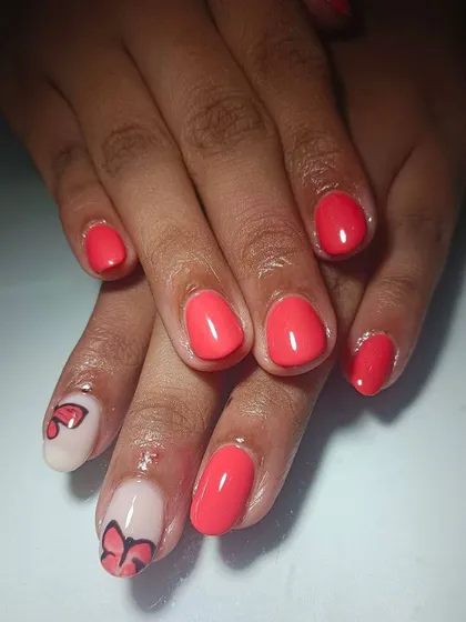 A sweet and simple design with bright coral polish and a hand-painted butterfly accent nail on a negative space background.