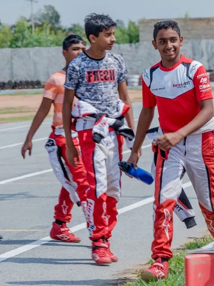 Young drivers in their race suits walking the track, building camaraderie and discussing the challenges of the circuit.