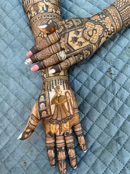 A close-up of a bridal mehendi with a groom portrait and the initial 'S'.