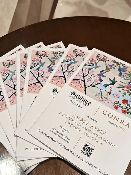 A stack of invitations for the 'Art Soirée', featuring a beautiful painting of birds and cherry blossoms.