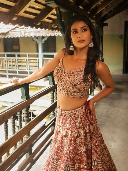 Poornima looking stunning in a traditional setting. The makeup is glamorous, with a focus on her eyes, and her hair is styled in soft waves.