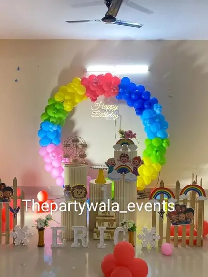 A very colorful Cocomelon party with a rainbow balloon arch. The character cutouts and picket fence create a fun and inviting space for the little ones.
