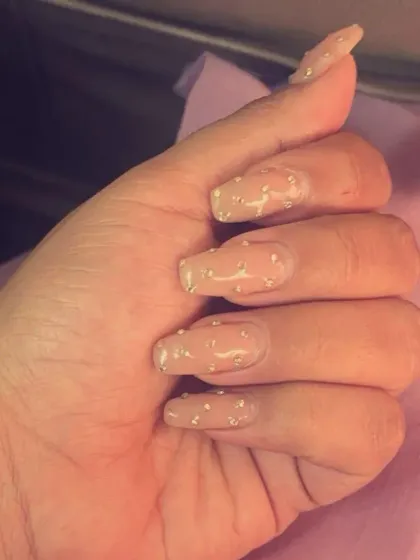 A chic and understated look with sheer pink coffin-shaped nails, each dotted with a single tiny silver rhinestone for a minimalist sparkle.