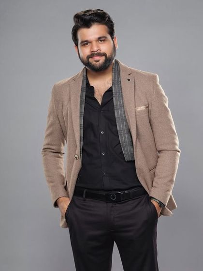 A relaxed portrait showing the layering of the scarf and unbuttoned shirt under the blazer for a modern red carpet look.