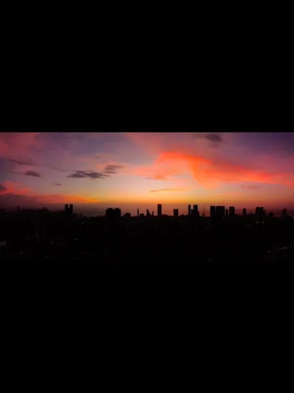 A letterboxed panoramic shot of a dark Mumbai skyline, with a vibrant orange cloud formation glowing in the twilight sky.