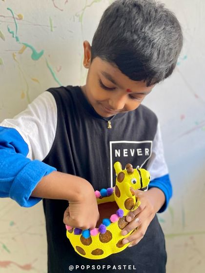 A young boy adds the finishing touches to his adorable giraffe planter, ready to take it home for his favorite plant.