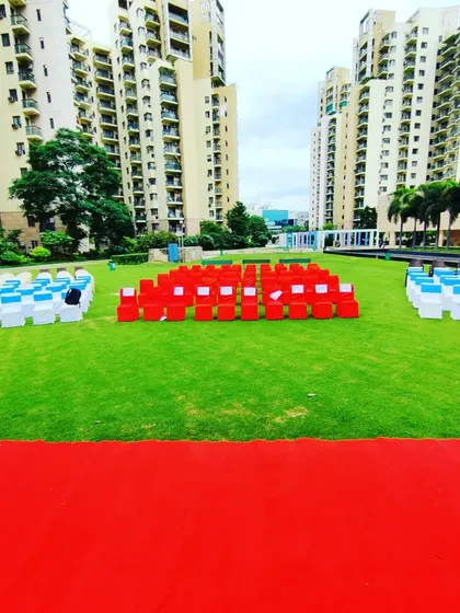 Preparing the seating arrangement for a flag hoisting ceremony at Uniworld Gardens. The chairs are neatly arranged in blocks of saffron, white, and green to represent the Indian flag.