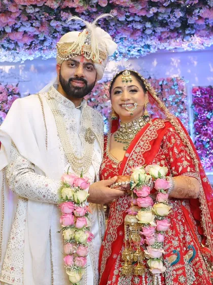 A classic portrait of the bride and groom. The makeup is balanced to look perfect against the elaborate floral backdrop.