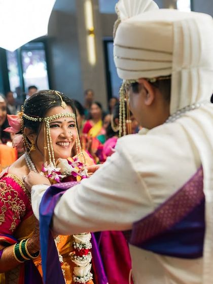 The groom places the garland on his smiling bride during the Varmala ceremony, surrounded by happy guests.