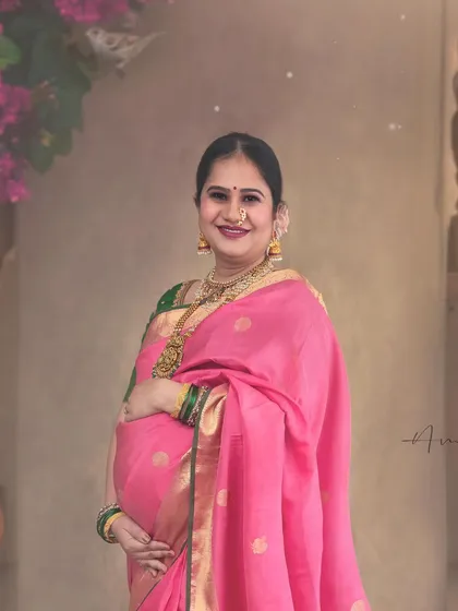A beautiful, smiling portrait that captures the pure happiness of this special time. The focus is on her radiant expression, complemented by the rich colors of her saree and the artistic setting.
