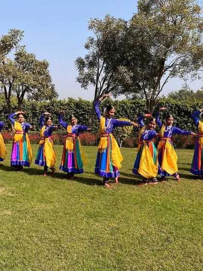 A full group shot of my students in their vibrant multi colored costumes, striking a pose in an outdoor setting after a successful performance.