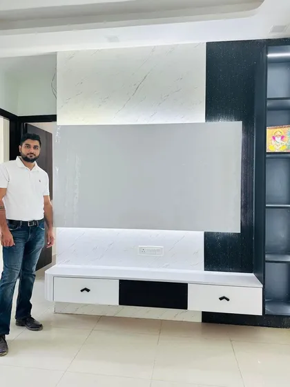 A full view of the completed TV unit at Nirala Estate, featuring a black and white design with a backlit panel and open shelving.