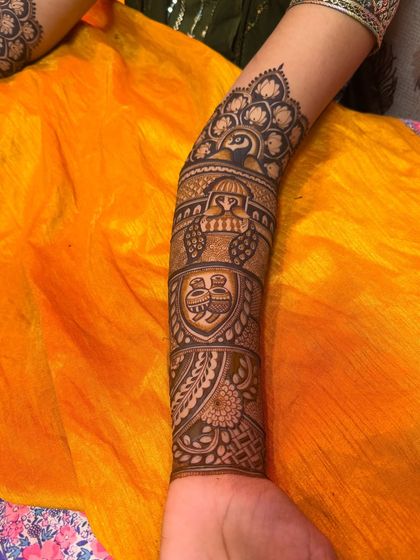 A close-up of an arm design featuring a peacock and traditional Indian architecture. The use of bold and fine lines creates a beautiful texture.