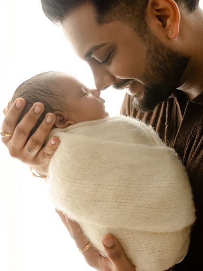 A tender moment between a father and his newborn. The father's gentle expression as he looks at his baby shows a deep, quiet love.