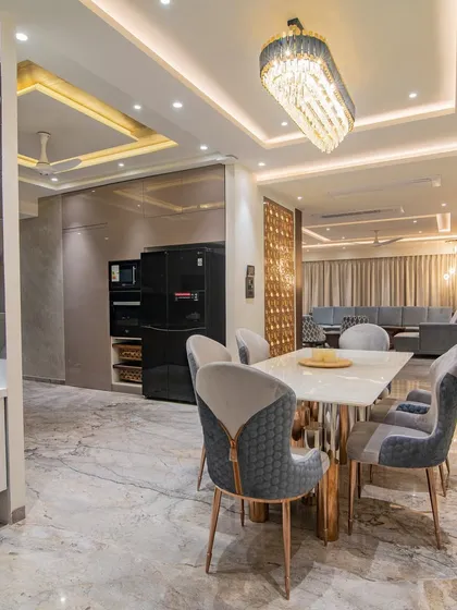 This open-plan dining area seamlessly connects to the living space. The design features a marble-top dining table with elegant upholstered chairs and a stunning crystal chandelier, perfect for family meals and formal gatherings.