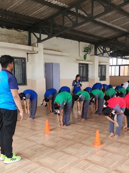 A group of students practices a forward bend during a yoga session. We teach proper form to help them improve flexibility and learn the fundamentals of yoga.