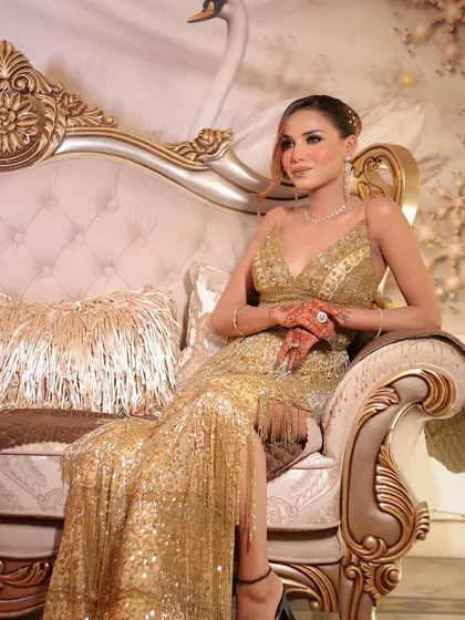 A regal pose on a classic sofa. The lighting beautifully captures the shimmer of the dress and the glow of her makeup.