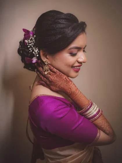 A soft and elegant portrait of a bride on her engagement day. The side profile, gentle smile, and focus on her floral hair bun and mehndi create a timeless and graceful image.