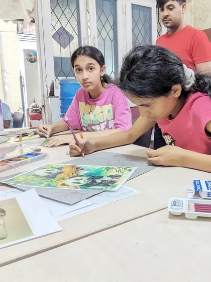 An instructor observing and guiding students as they work on their pastel drawings.