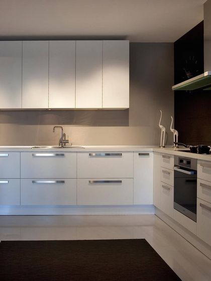 A clean, all-white modular kitchen design. The handle-less cabinets and simple layout create a bright, uncluttered space that feels both modern and timeless.