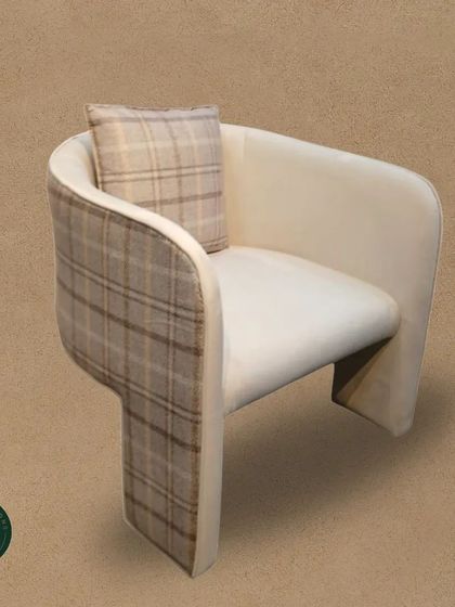 This unique armchair features a creative use of plaid fabric on its exterior, contrasted with a clean white seat. The unusual T-shaped back legs add to its distinctive, modern character.