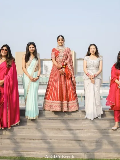The bride and her powerful tribe. She stands confidently with her bridesmaids and family, all dressed in elegant attire.