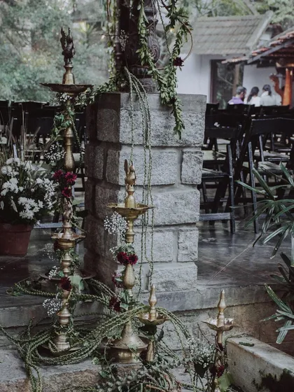 Traditional South Indian brass lamps (diyas) adorned with locally grown flowers and fruits, adding an authentic and sacred touch to the wedding decor.