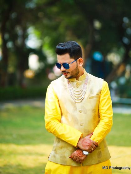 A close-up of the groom's Haldi look. The multi-strand pearl necklace adds a touch of elegance to the festive attire.