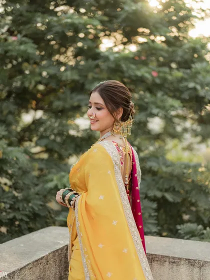 A side profile of the bride, highlighting her intricate hairstyle, traditional nath (nose ring), and heavy gold jewelry. This detailed shot focuses on the key elements of a Maharashtrian bridal look.