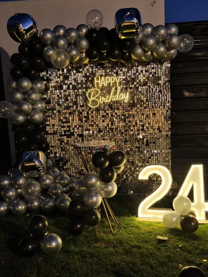 A nighttime shot of the 24th birthday silver sequin wall, showing how the lights and balloons create a festive party atmosphere.