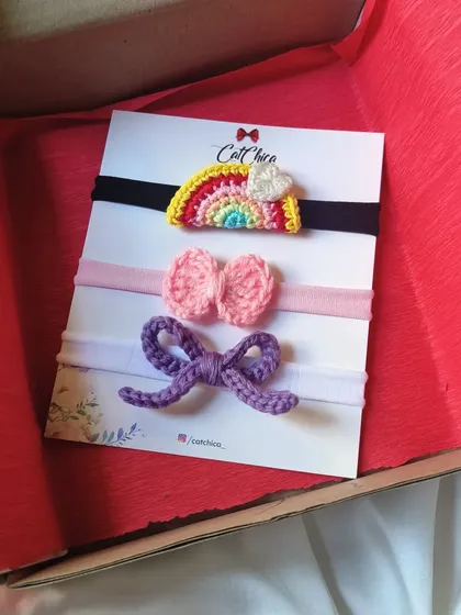 Our newborn headband set of three, neatly packed in a gift box with red tissue paper. It's all ready to be gifted for a baby shower or birth announcement.