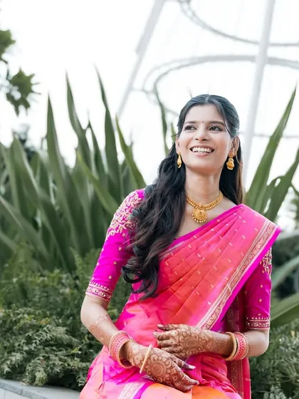 A happy bride in a bright pink saree, enjoying her outdoor photoshoot.