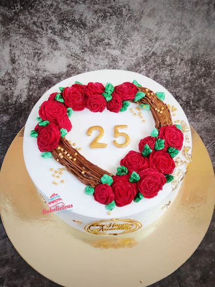 A lovely cake for a 25th anniversary, featuring a heart-shaped wreath made of tiny red buttercream roses.